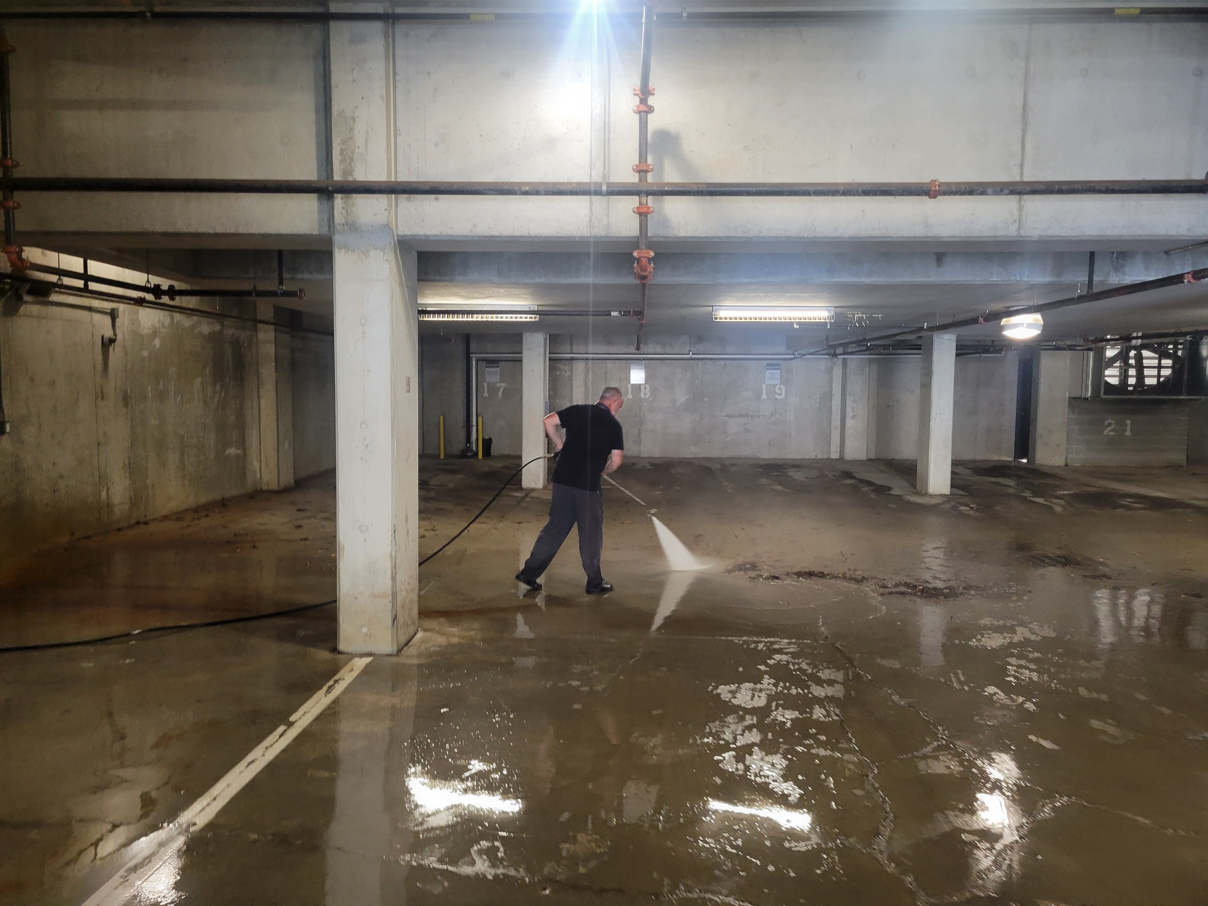 Pressure washing the floor of a commercial parking garage