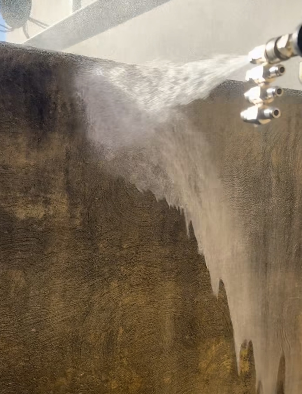 Low-pressure cleaning solution being applied to a stained exterior surface